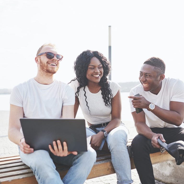 Beautiful multi ethnic friends using a laptop in the Street. Youth lifestyle concept