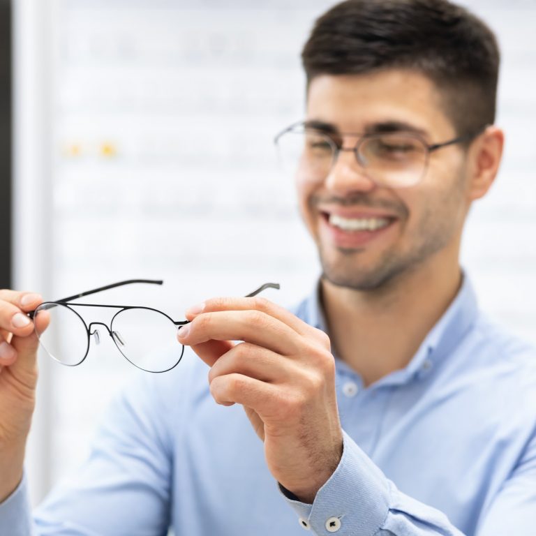 Happy man choosing glasses at optics store