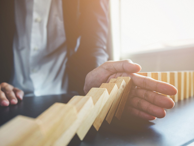 Problem Solving,Close up view on hand of business woman stopping falling blocks on table for concept about taking responsibility.